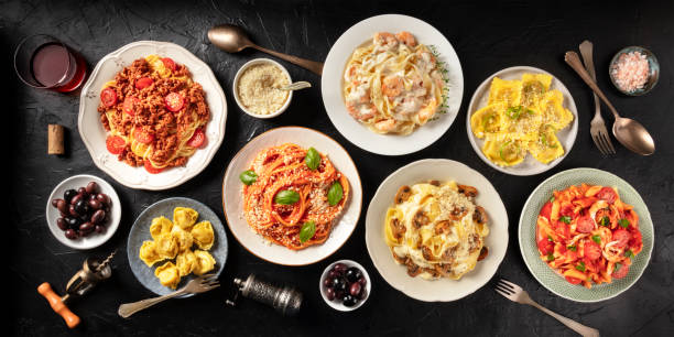 pasta. assortment of italian pasta dishes, including spaghetti bolognese, penne with chicken, tortellini, ravioli and others, shot from the top on a black background - italian cuisine minced meat tomato herb imagens e fotografias de stock