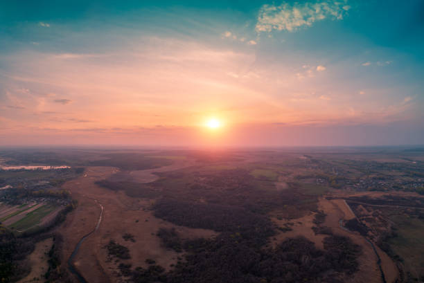 istock Spring rural landscape in the evening with beautiful burning sky. Aerial view. Panoramic view of pine forest, fields, river, and village during blazing sunset 1222771678