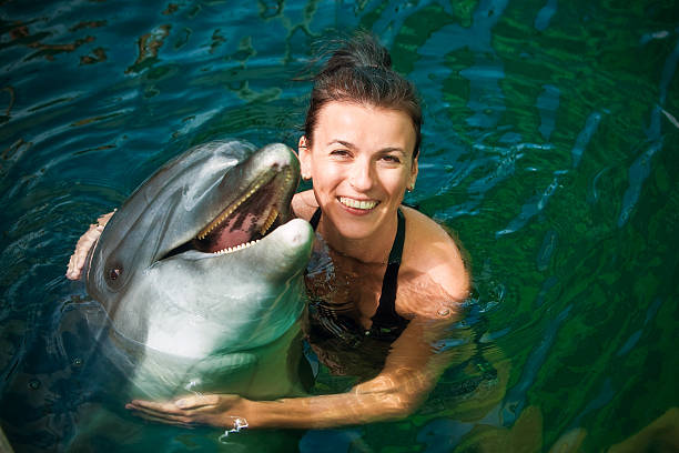 A woman hugging a dolphin in a pool stock photo