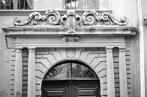 The ornament of the old doors is made of stone. Black-and-white fragment.