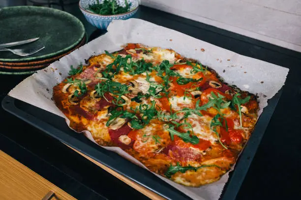 May 1, 2020 - Warsaw, Poland: tasty crusty freshly baked and straight from oven rectangular pizza in a domestic kitchen on a cooking stove top