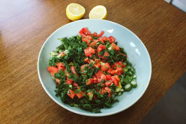April 30, 2020 - Warsaw, Poland:Healthy green and red vegetable salad - vegan vegetarian raw food diet, healthy eating - tomatoes, paprika, dill, asparagus in large navy bowl on a wooden table, close up