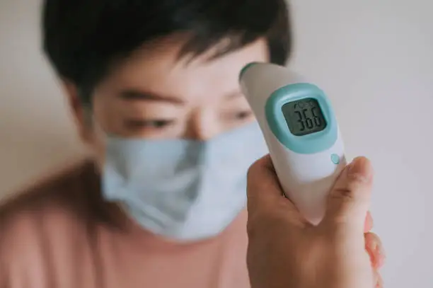 Photo of measuring body temperature using digital infrared thermometer for prevention and security measurement precaution