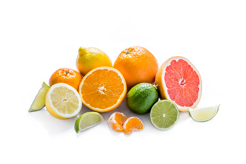 Front view of various kinds of whole and sliced citrus fruits like grapefruit, orange, tangerine, lime and lemon isolated at the center of the image on white background.