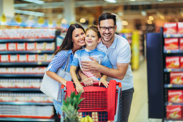 Happy family with child and shopping cart buying food at grocery store or supermarket Happy family with child and shopping cart buying food at grocery store or supermarket friday stock pictures, royalty-free photos & images