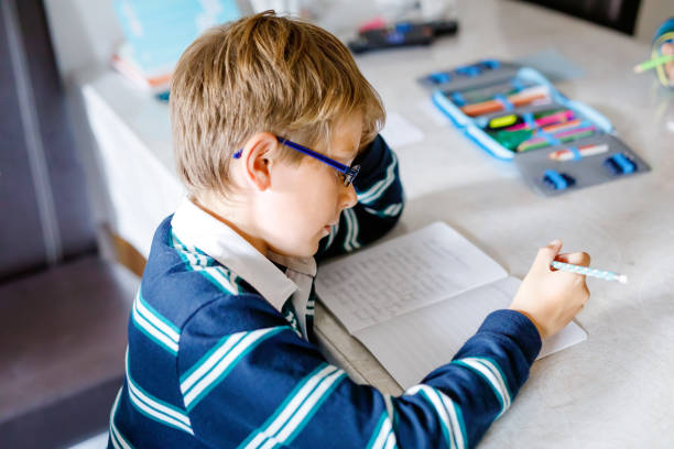 istock Hard-working happy school kid boy making homework during quarantine time from corona pandemic disease. Healthy child writing with pen, staying at home. Homeschooling concept 1222783178