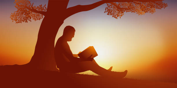 istock Holiday concept with a man sitting at the foot of a tree who reads a free while enjoying a moment of calm. 1222783375