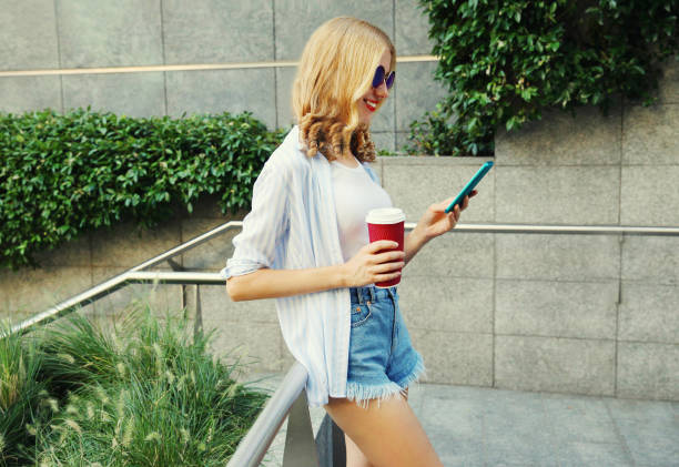 istock smiling young woman using smartphone with coffee cup in the city 1222786811