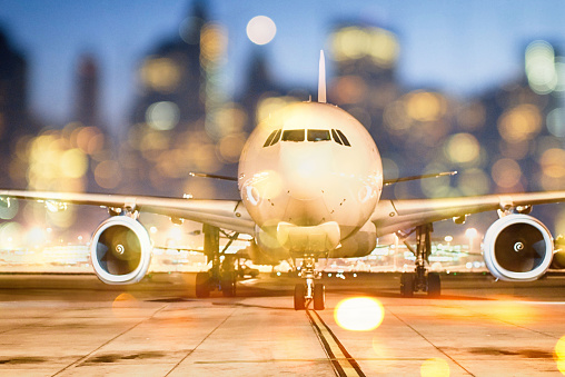 Airplane on ground, cityscape with lights in the background