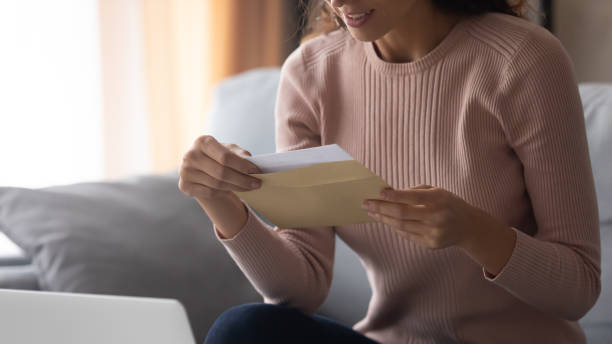 istock Smiling young woman holding envelope with paper letter. 1222788479