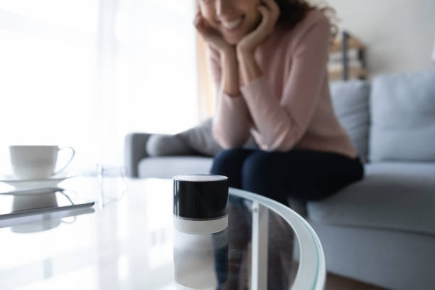 istock Happy woman looking at compact voice assistant on glass table. 1222788531