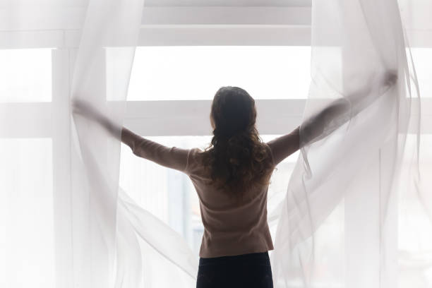 istock Back rear view happy young woman opening light curtains. 1222788540