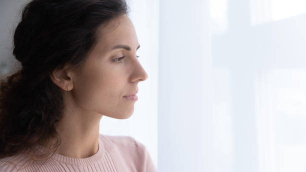 istock Thoughtful young woman looking away through window. 1222788594