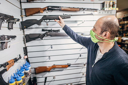 One mature man preparing his shop for opening. His gun shop is back in business after coronavirus lockdown.