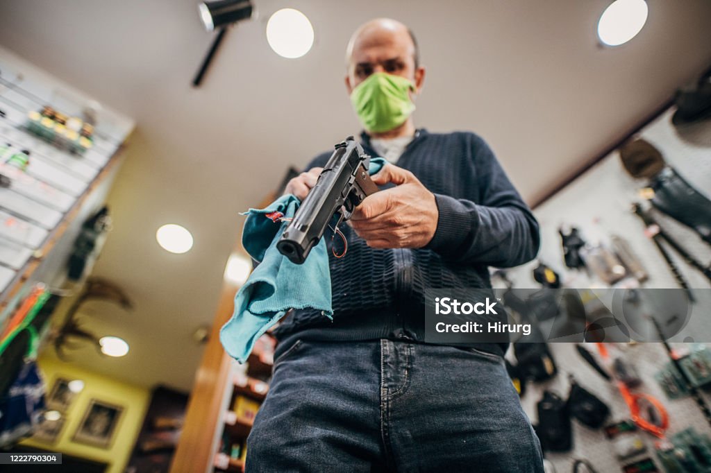 One mature man disinfecting his shop before opening One mature man disinfecting his shop before opening. His gun shop is back in business after coronavirus lockdown. Gun Shop Stock Photo