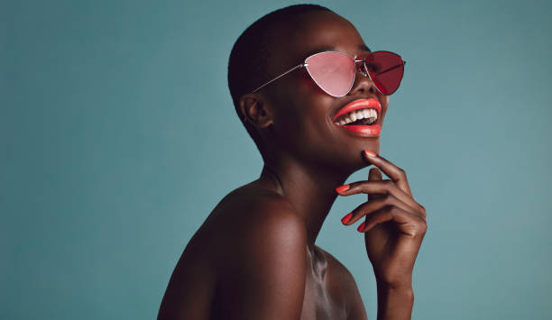 African female model with funky sunglasses Close up shot of beautiful woman in sunglasses and red lips against grey background. African female model with funky sunglasses. luxury eyewear stock pictures, royalty-free photos & images