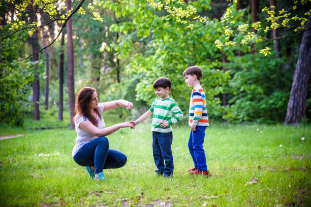 young woman mother applying insect repellent to her two son before forest hike beautiful summer day or evening. protecting children from biting insects at summer. active leisure with kids - insect repellant imagens e fotografias de stock