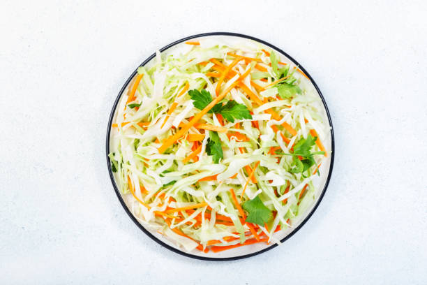 白いキッチンテーブルの背景にニンジンと白キャベツサラダコールスロー。トップ ビュー、コピースペース - sauerkraut salad coleslaw cabbage ストックフォトと画像