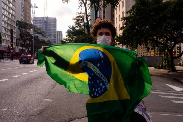 коронавирус пандемии и защиты. ношение facemask и продажа флагов - flag brazil brazilian flag dirty стоковые фото и изображения