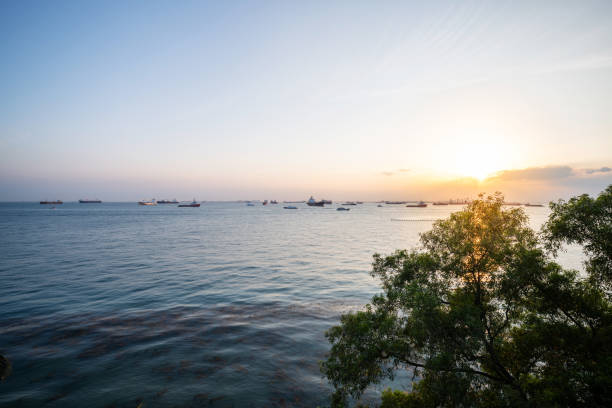 Singapore: Transportation and Container ships wait on the ocean in front of the port of Singapore.