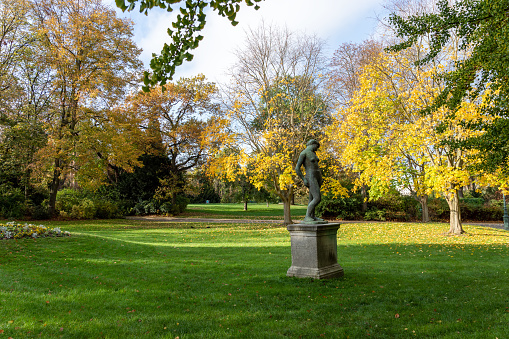 Paris, France - November 09 2019: Parc Montsouris in autumn with statue in foreground - Paris, France