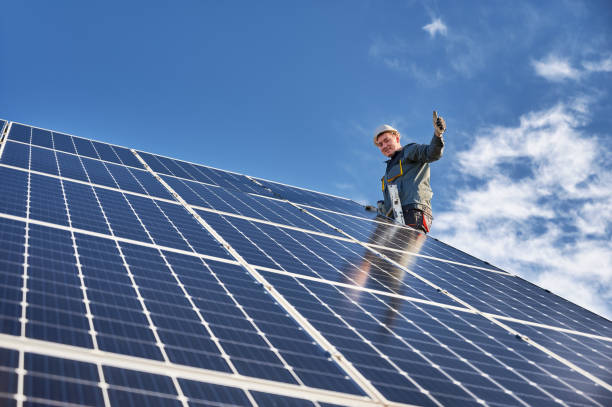 joyful technician installing solar panel under blue sky. - solar power station solar panel energy electrician imagens e fotografias de stock