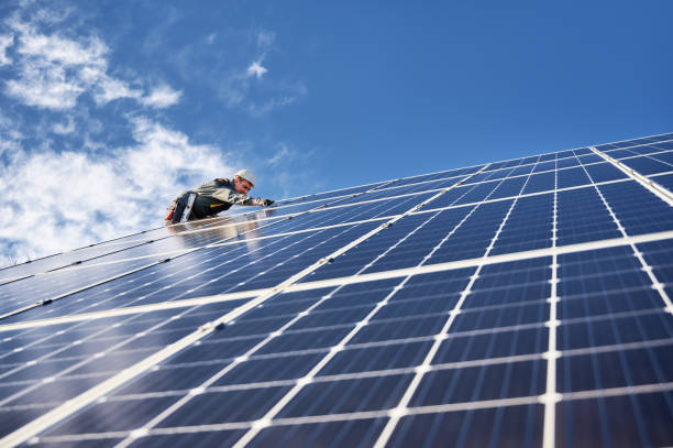 electricista hombre instalando panel solar bajo el cielo azul. - solar panel engineer solar power station solar energy fotografías e imágenes de stock