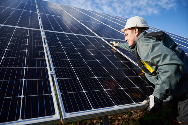 workman standing on the ground trying to fasten solar batteries together, installing process - solar power station solar panel energy electrician imagens e fotografias de stock