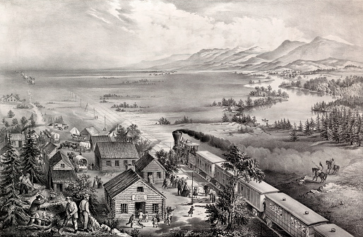 Vintage illustration showcases the Westward Expansion of America as a steam railroad train with many passengers embarks for the West. Covered wagons can also be seen departing from this settlement. Considering the Transcontinental Railroad was completed in 1869, this scene most likely takes place afterwards.