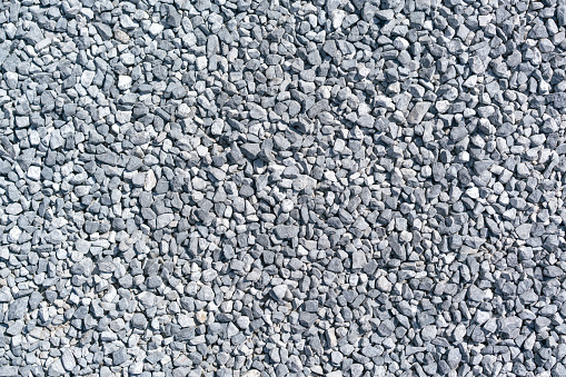 Granite gravel, stones, crushed stone close-up. Rough seamless texture, construction material background.