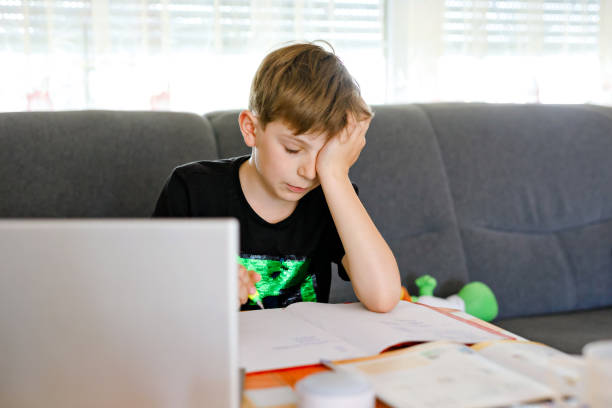 istock Upset school kid boy making homework during quarantine time from corona pandemic disease. Frustrated sad boy learning staying at home with video via laptop. Homeschooling concept 1222816713