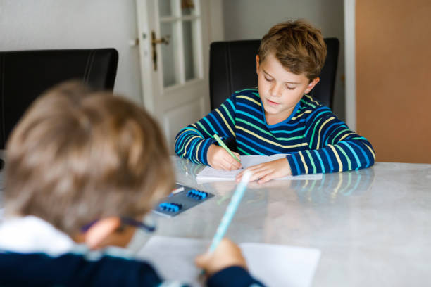 istock Two hard-working school kids boys making homework during quarantine time from corona and covin 19 pandemic disease. Children, brothers writing with pen, staying at home. Homeschooling concept. 1222816903