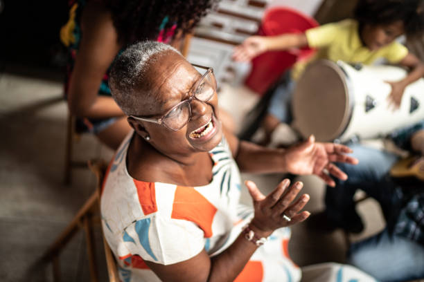 retrato de la abuela tocando música en casa - con la familia en el fondo - carnaval de brasil fotografías e imágenes de stock