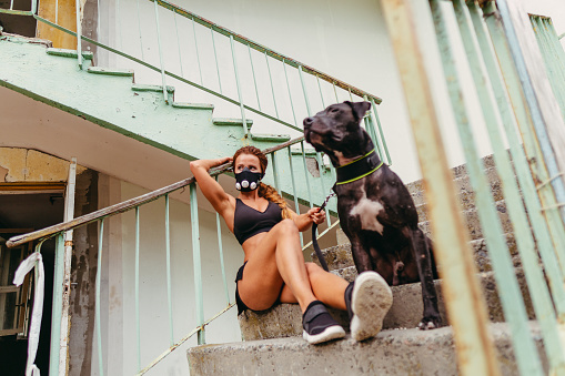 Post apocalypse. Athletic girl in a hypoxic mask holds a dog on a leash.