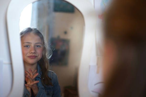 Portrait of a young girl looking in the mirror in front of her vanity table stock photo