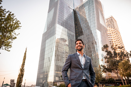 Portrait of a handsome smiling businessman outside his office in the sunset