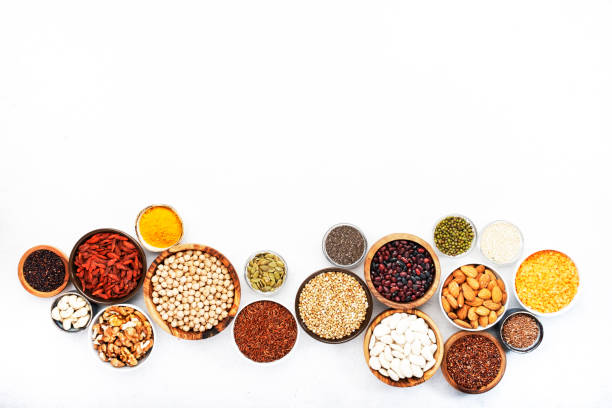 Various superfoods, legumes, cereals, nuts, seeds in bowls on white background. Superfood as chia, spirulina, beans, goji berries, quinoa, turmeric, mung bean, buckwheat, lentils, flax seed, wild rice and almond. Copy space, top view varios superalimentos, legumbres, cereales, nueces, semillas en cuencos sobre fondo blanco. superalimento como chía, espirulina, frijoles, bayas de goji, quinua, cúrcuma, frijol mung, trigo sarraceno, lentejas, semillas de lino, arroz silvestre y almendr