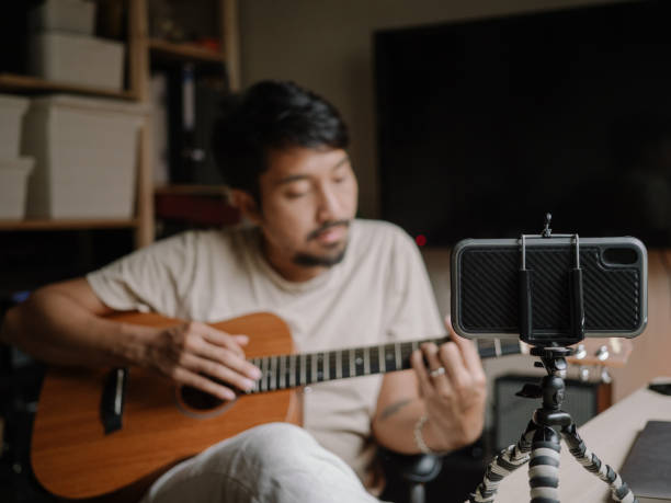 istock Hipster Man Giving Guitar lesson On Internet With Video Tutorial At Home. 1222822985