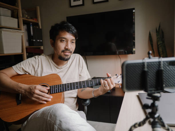 istock Hipster Man Giving Guitar lesson On Internet With Video Tutorial At Home. 1222822988