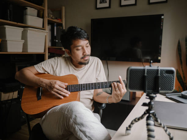 istock Asian man learning to playing guitar in room at home 1222823026