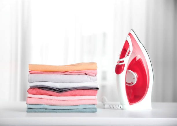 pile de vêtements colorés en coton avec du fer. concept de ménage. la lessive empilée. - iron table photos et images de collection