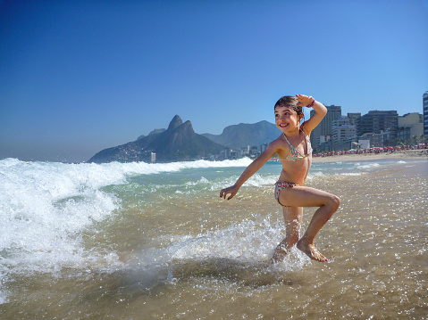 A gril runs from a wave in Ipanema beach, Rio de Janeiro, Beach.