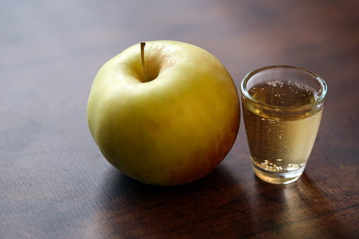 Apple drink and an apple on a wooden background.