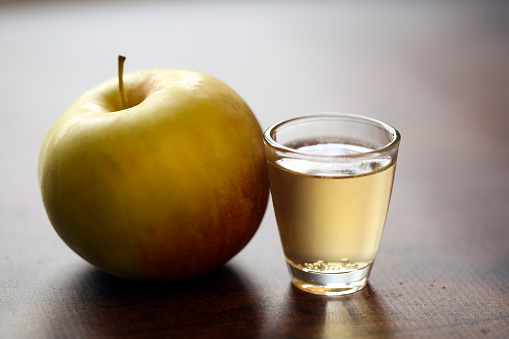 Apple schnapps drink and an apple on a wooden background.