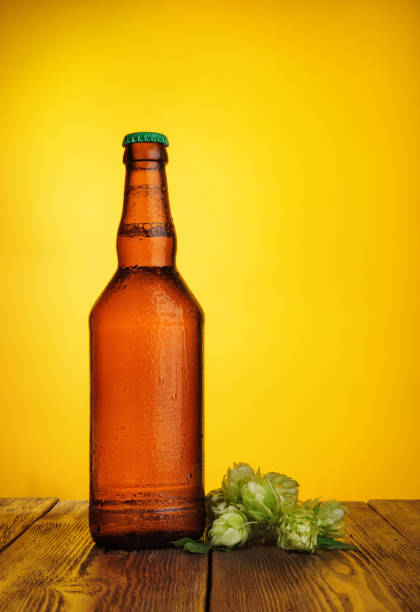 istock Bottle with drops of beer with hops on yellow. 1222826470