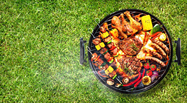 Top view of assorted delicious grilled meat with vegetables on barbecue grill with smoke Top view of assorted delicious grilled meat with vegetables on barbecue grill with smoke and flames in green grass metal grate stock pictures, royalty-free photos & images