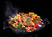 Assorted delicious grilled meat with vegetables on barbecue isolated on black background