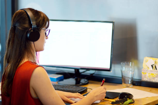 istock Woman working in an office using computer and headphones 1222827891
