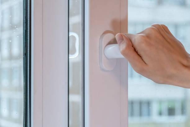 istock Female hand opens a window with drops on the glass on a cloudy rainy day 1222828055