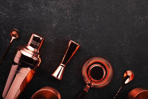 istock Copper bar tools and accessories for making cocktail. Shaker, jigger, strainer, spoon, tongs, muddler. Alcohol drink and beverages preparation concept. Black background, top view, copy space 1222829523
